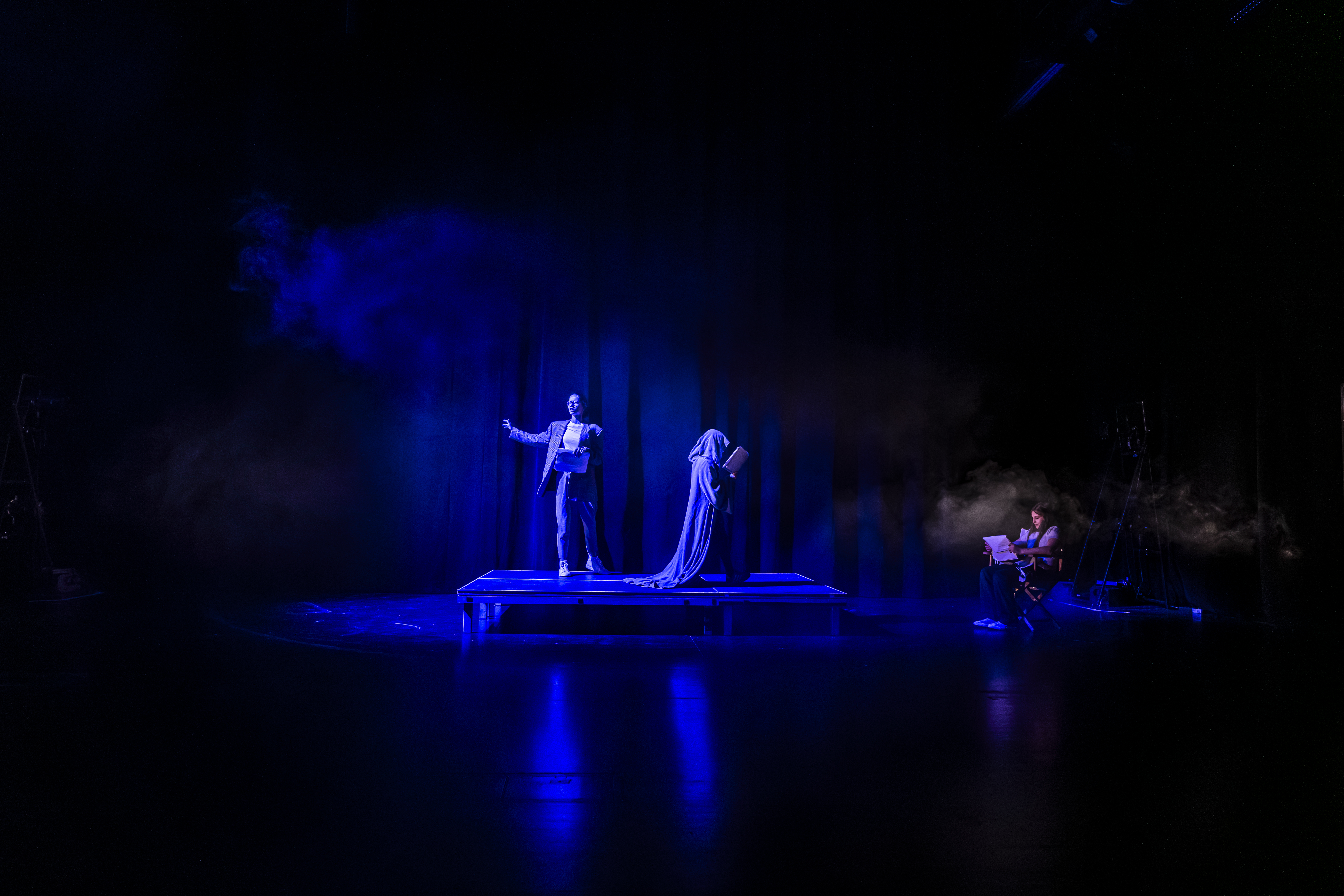 Die Silhouette einer Person hinter einem Vorhang. Die Person hält ein Mikrofon.